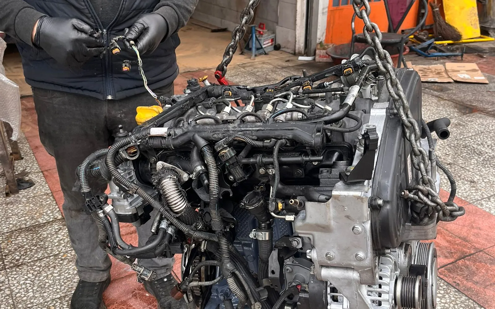 SE & FE Garaj ustası sökülmüş motoru vinç zinciriyle taşırken